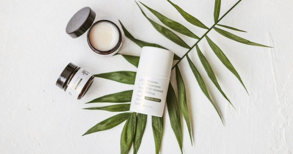 Baume et cremes cosmetiques au CBD poses sur une feuille de palmier, routine peau naturelle